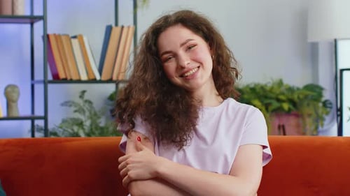 Woman Smiling at Camera on Orange Sofa