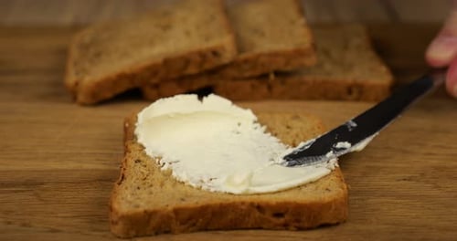 Cream Cheese Being Spread Onto Slice of Bread