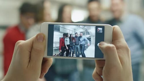 First view footage of a person taking a picture of students with a smartphone.