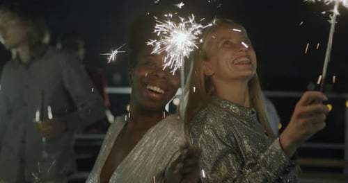 Smiling Young Adults Celebrate with Sparklers at Night