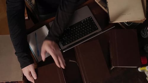 Person Studying, Typing on Laptop with Books