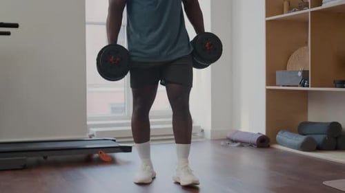 African American Man Performing Bicep Curls with Dumbbells in Home Gym