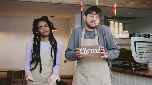 Two Multiracial Baristas Team at the Cafe Holds a Closed Sign During a Quiet Moment with Customers