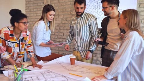 Group of young business people discussing architectural designs in office.