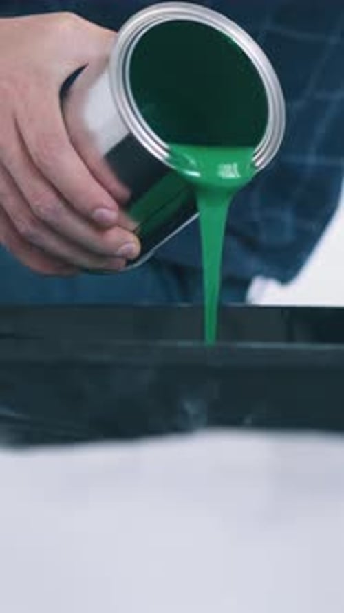 Man Pours Green Paint Into Plastic Tray on Floor Closeup