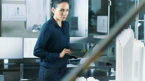 Female Architectural Designer Works on a Laptop, Engineering New Building Model for the Urban Plan