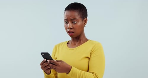 Shocked, black woman and smartphone with reaction, app and typing on a blue studio background