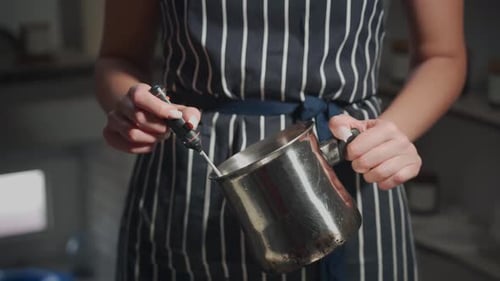The Process of Making Wax Scented Candles A Woman in a Striped Apron Checks the Temperature of