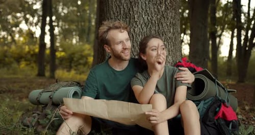 Couple Planning Hike Using Map in Forest