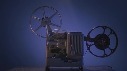 Vintage Film Projector with Reels Spinning in Dark Room