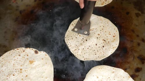 Hands Pressing Flatbread Cooking on Stove