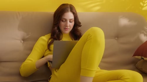 Woman Works on Laptop While Lounging on Couch