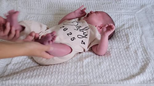 Crying Infant Lying on a Blanket is Soothed