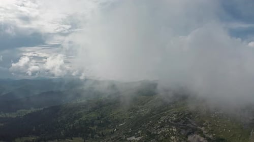 A Majestic Mountain Peak Surrounded By Fluffy Clouds Embracing the Serenity of Nature