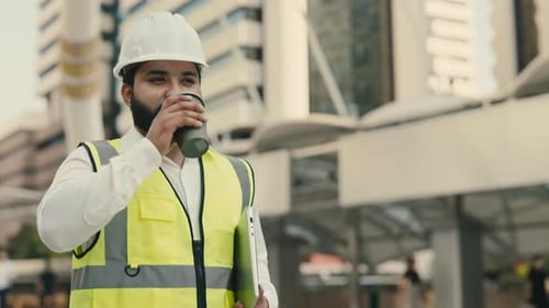 Portrait of Indian Foreman with Laptop Drinking Coffee Against Buildings