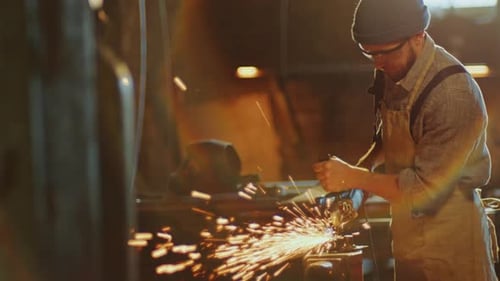 Schmied bearbeitet Metall mit Winkelschleifer in der Werkstatt