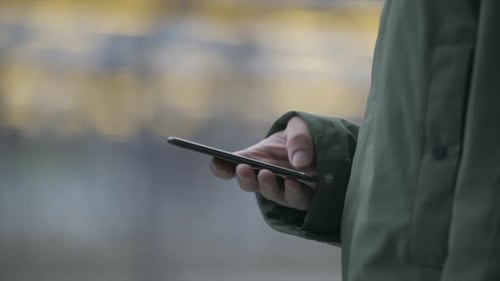 Close up of hands scrolling through a smartphone. Train station.