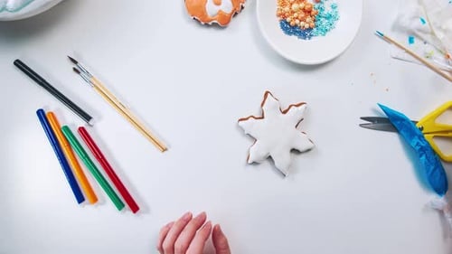 Women's Hands Decorate a Christmas Gingerbread Snowflake Shape