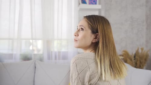 Thoughtful Woman Sitting on a Sofa Indoors