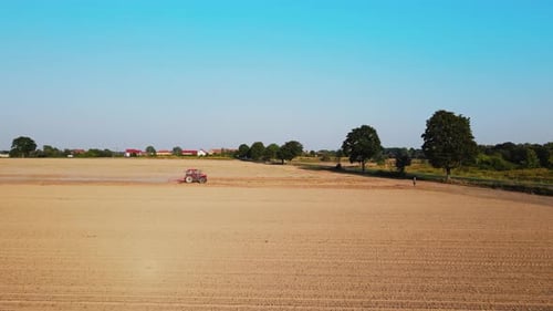 Tractor Working in Agricultural Field Cultivating and Plowing Dry Soil