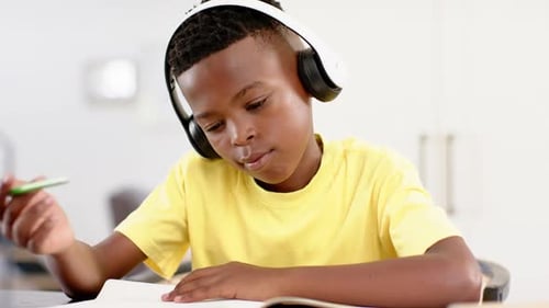 In school, child wearing headphones studying and writing in notebook