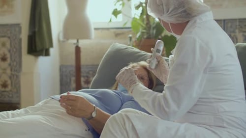 Doctor Taking Temperature of Woman with Nocontact Thermometer