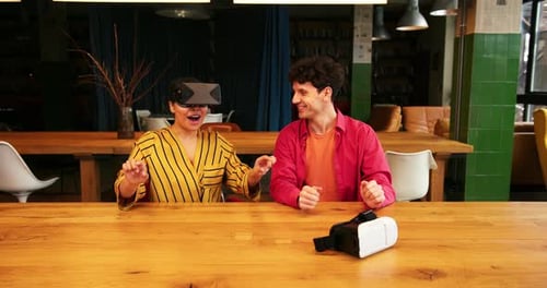 Freelancers felices y sonrientes que usan gafas de realidad virtual jugando a videojuegos sentados en una oficina moderna