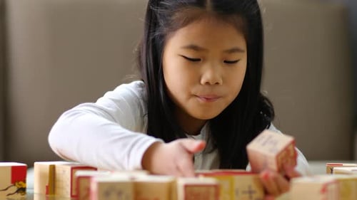 Enthusiastic Girl Playing with Wooden Math Blocks