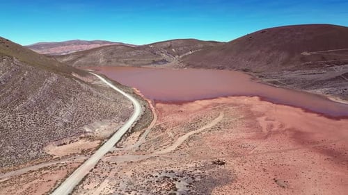 Aerial descends to red, muddy Laguna Llajuapampa in Peru foothills