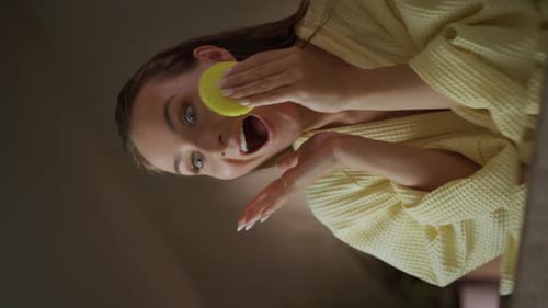 Woman Cleansing Face With Sponge in Yellow Robe