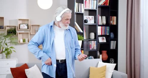 Energetic Senior Man Dancing with Headphones Indoors