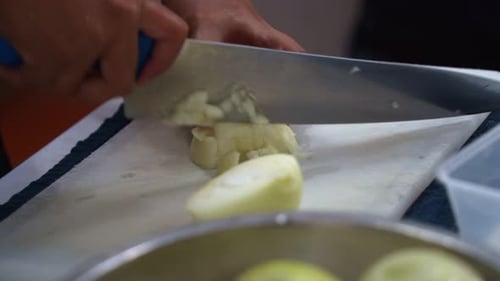 Professional kitchen hand preparing the ingredients for restaurant operation, brunoise cut the onion