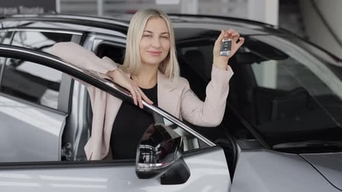 Happy business woman showing car key in dealership
