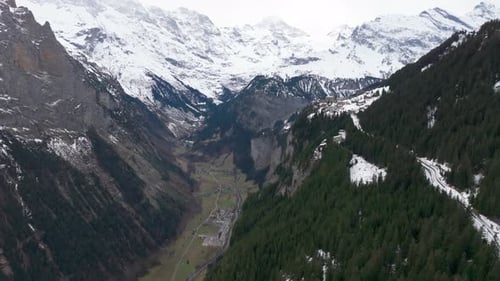 Impressive Switzerland mountain valley panorama with forest and snowy peaks