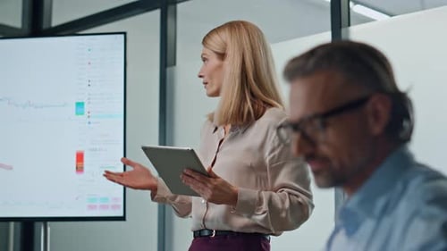 Inspired businesswoman pointing screen mentoring team in modern office