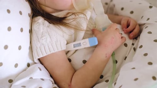 Gros plan d'un thermomètre à haute température sous le bras d'un enfant malade.
