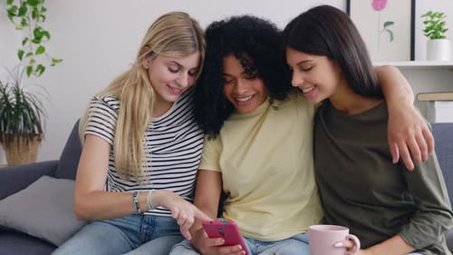 Drei glückliche junge Mädchen haben Spaß daran, soziale Medien auf der Smartphone-App zu schauen