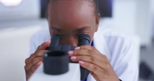 Scientist Looking Through Microscope in Clean Lab