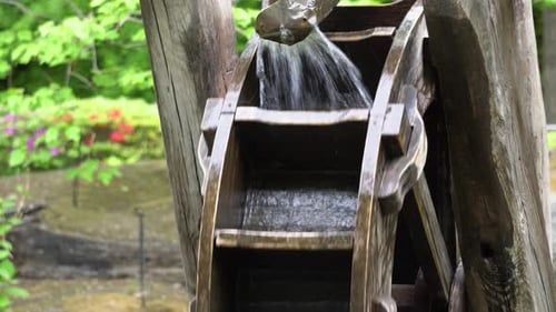 Wasser fließt in die Holzteile des traditionellen koreanischen Wasserrads im Namsan Park, Südkorea