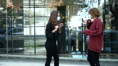 covid, social distancing - girls in the street greet each other with elbow