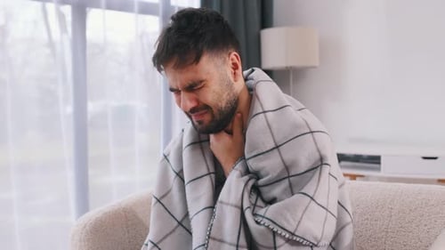 Adult Man with Sore Throat Wrapped in Blanket