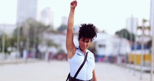 Woman Raises Fist in Defiance in Urban Setting