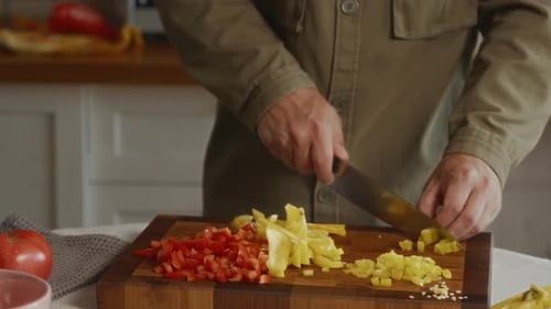 Man dicing colorful peppers in bright kitchen