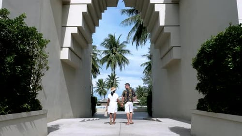 Couple Walking Hand in Hand Toward Tropical Beach