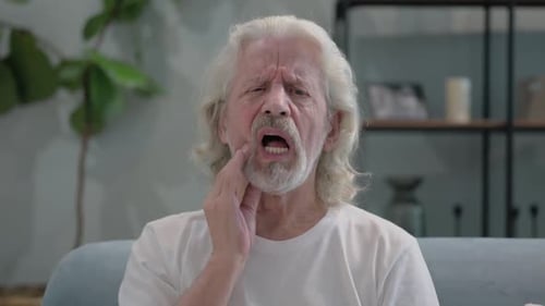 Senior Man Experiences Toothache at Home on Sofa
