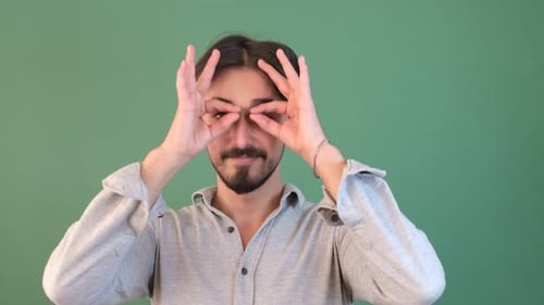Man Makes Binocular Gesture with Hands, Smiles