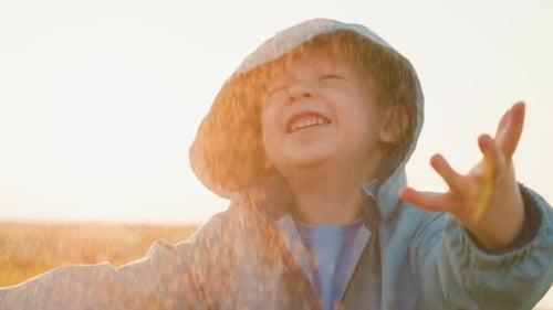 Smiling Child Playing in the Rain Outdoors