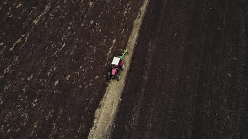 Red tractor plowing the field in Ukraine