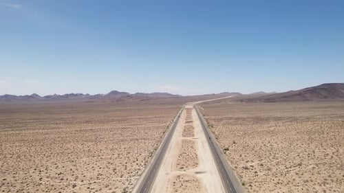 Cars and trucks driving on highway in desert. Aerial view of area with arid sandy soil and little ve