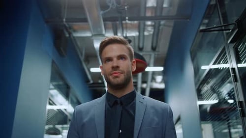 Handsome businessman walking with confidence in modern corporate office hallway